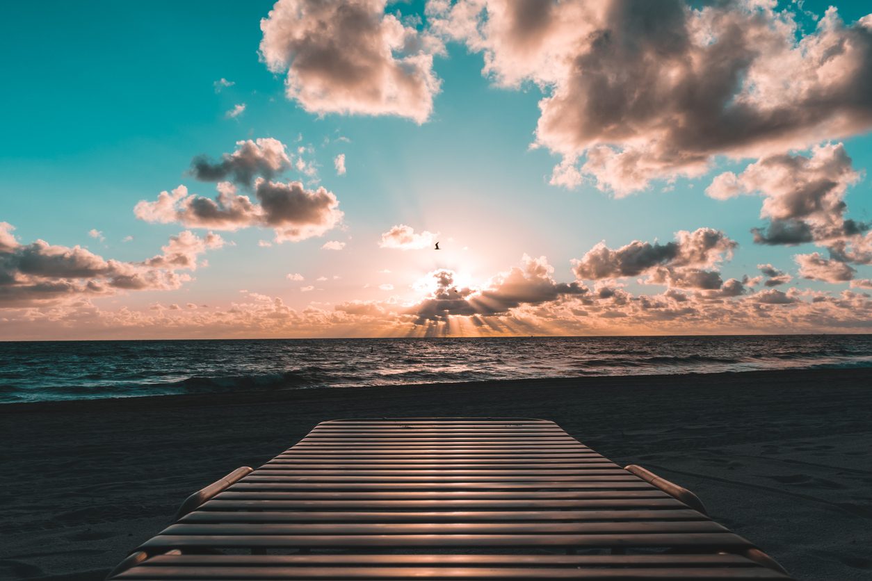Calm ocean at sunrise with a boardwalk leading toward the horizon
